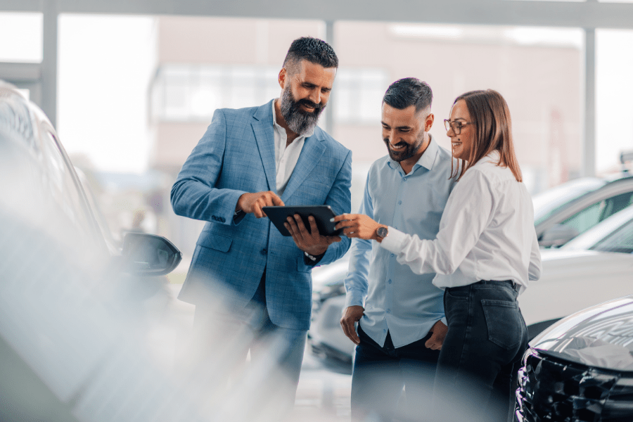 Conseiller automobile présentant une offre sur tablette à des clients dans une concession