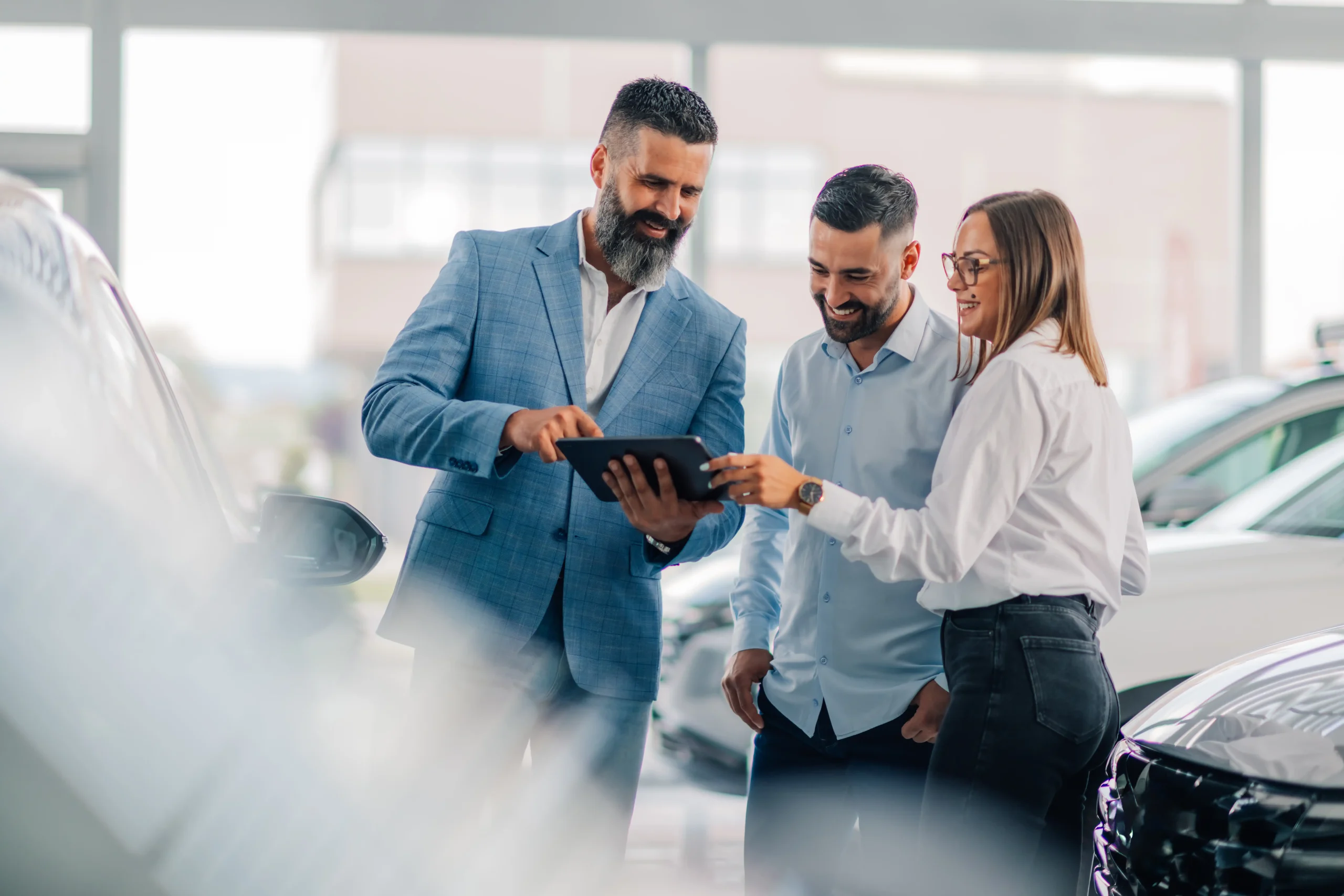 Conseiller automobile présentant une offre sur tablette à des clients dans une concession